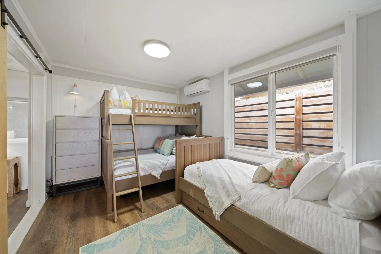 Un dormitorio con literas, una cómoda y una ventana grande.