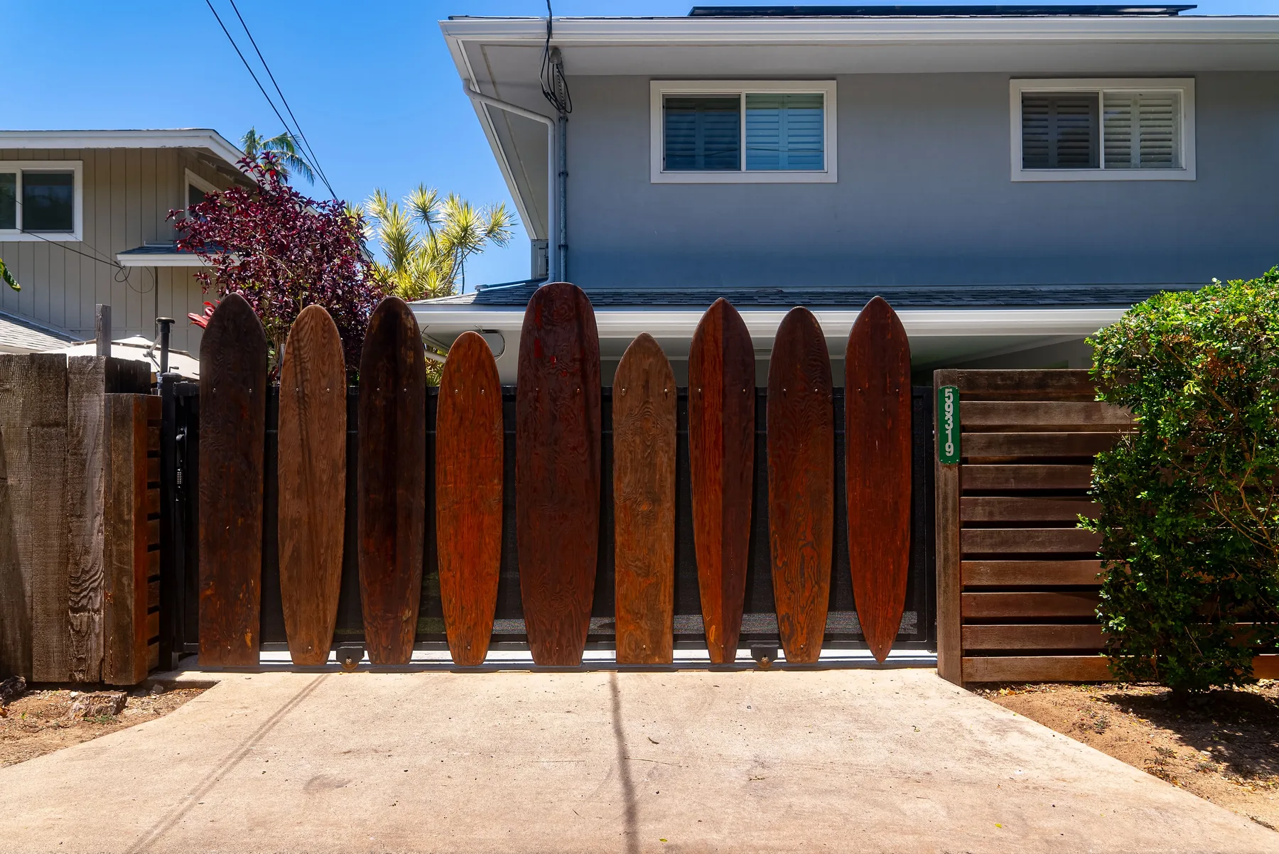 Una puerta de madera y entrada para autos frente a una casa de dos plantas.