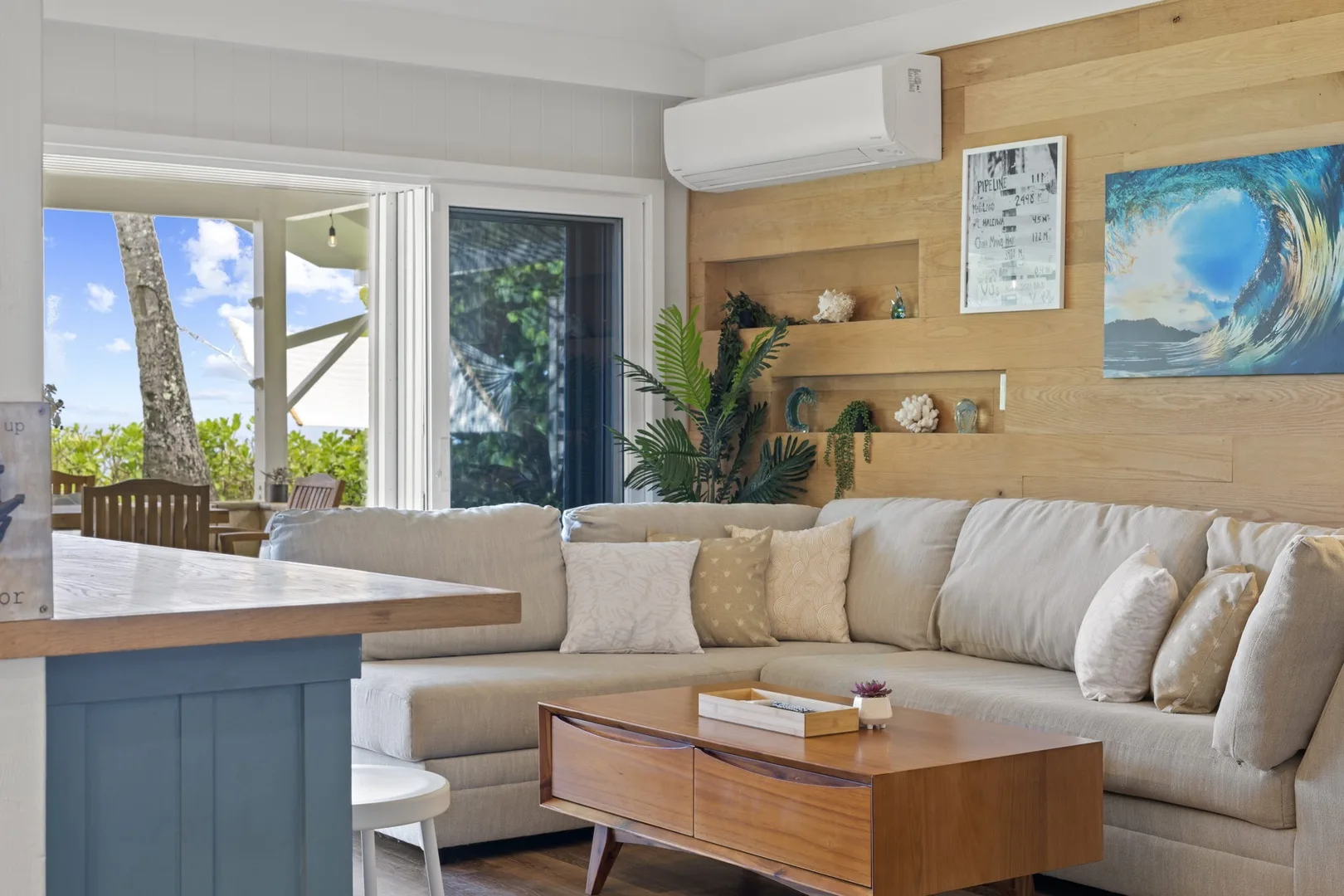 Una sala luminosa con sofá seccional, mesa de centro de madera y ventanales.