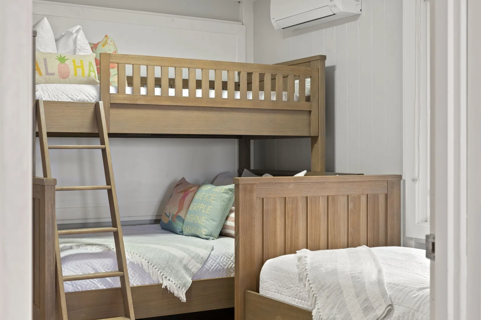 Un dormitorio con una litera de madera y ropa de cama clara.
