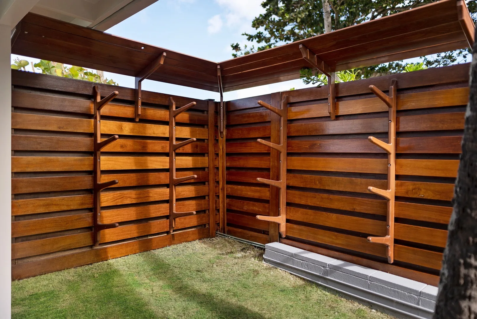 Un pequeño patio exterior está rodeado por una cerca de madera con repisas integradas.