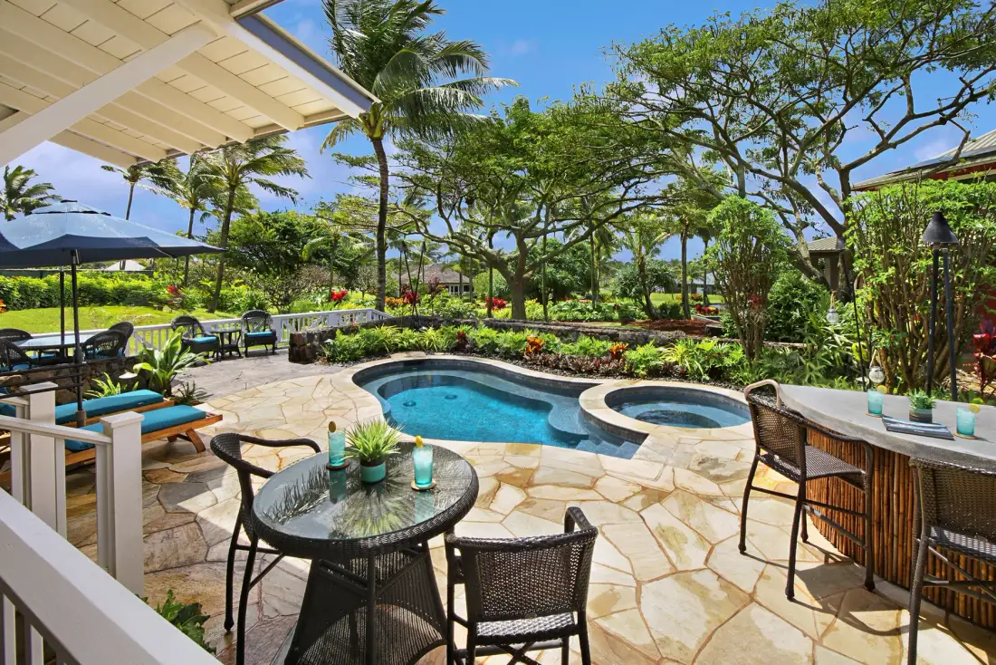 A landscaped outdoor patio with a curved swimming pool and seating.