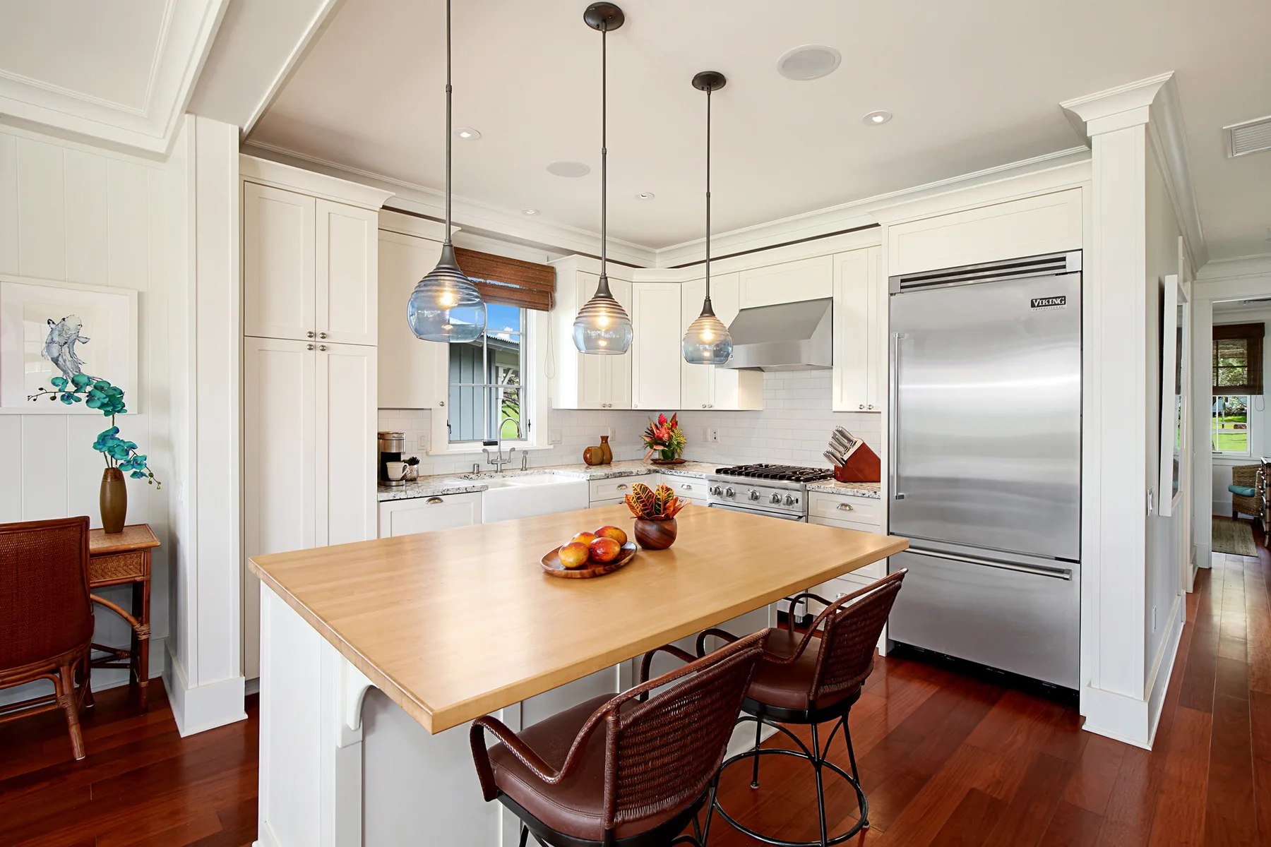 A bright kitchen features a large island with pendant lights and stainless steel appliances.