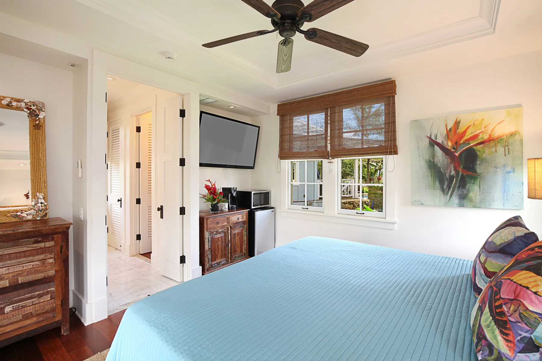 A bedroom with a bed beneath a window and a ceiling fan overhead.