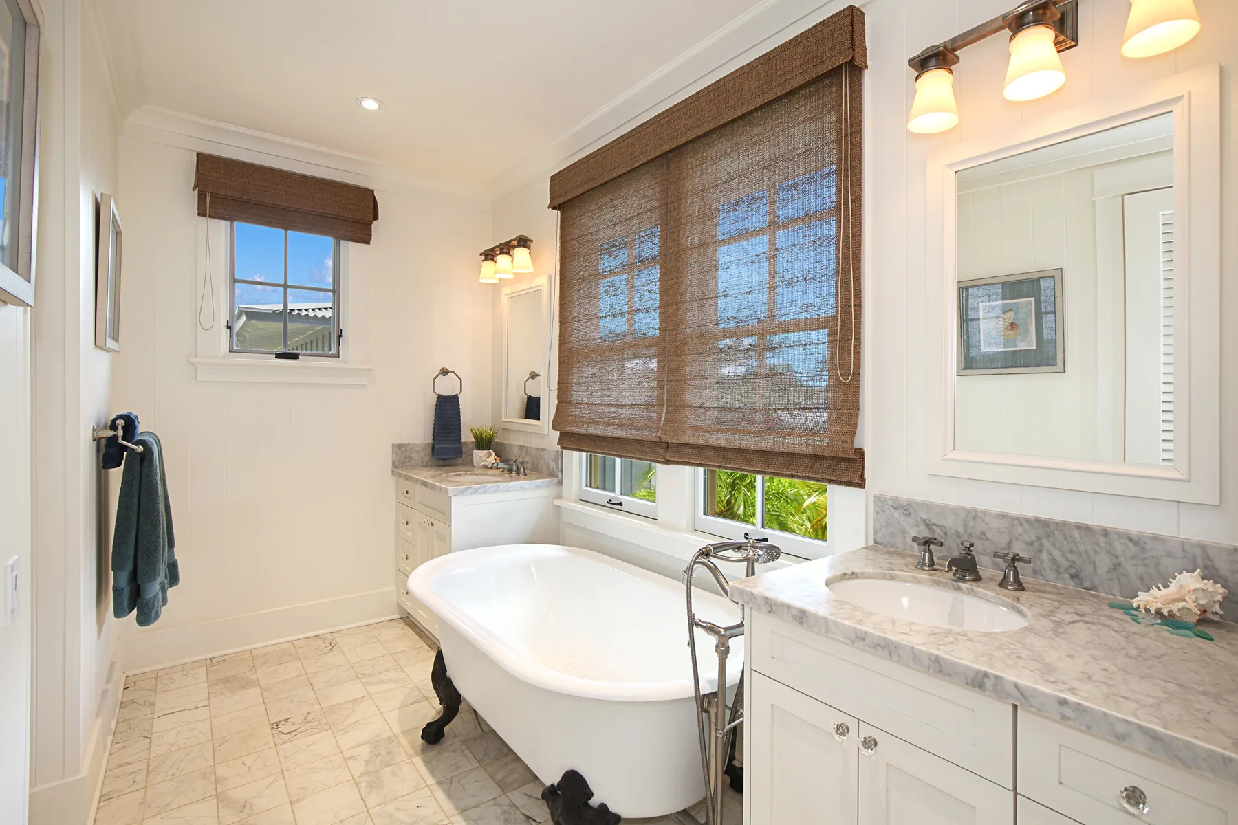 A bright bathroom with a freestanding bathtub and a marble vanity.