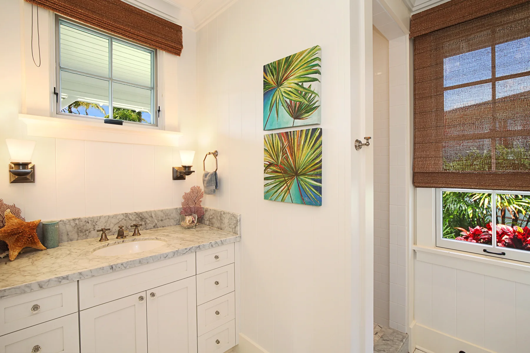 A bright bathroom vanity with a stone countertop sits beneath a window.