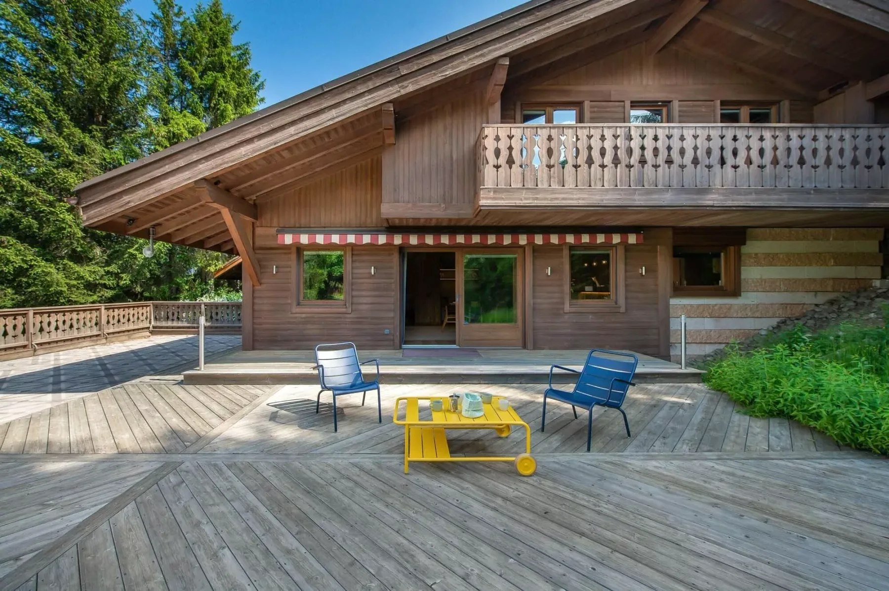 Un chalet de madera da a una amplia terraza con asientos al aire libre.
