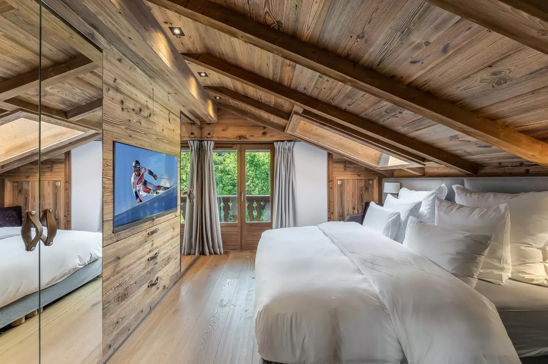 Un dormitorio con una cama grande bajo un techo de madera inclinado.