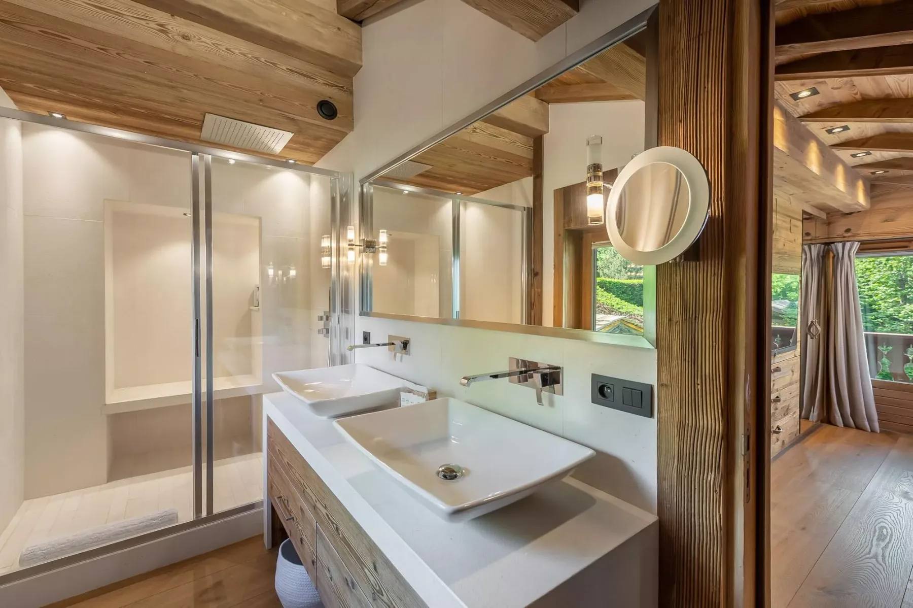 Un baño con ducha de vidrio y un amplio lavabo bajo un espejo.