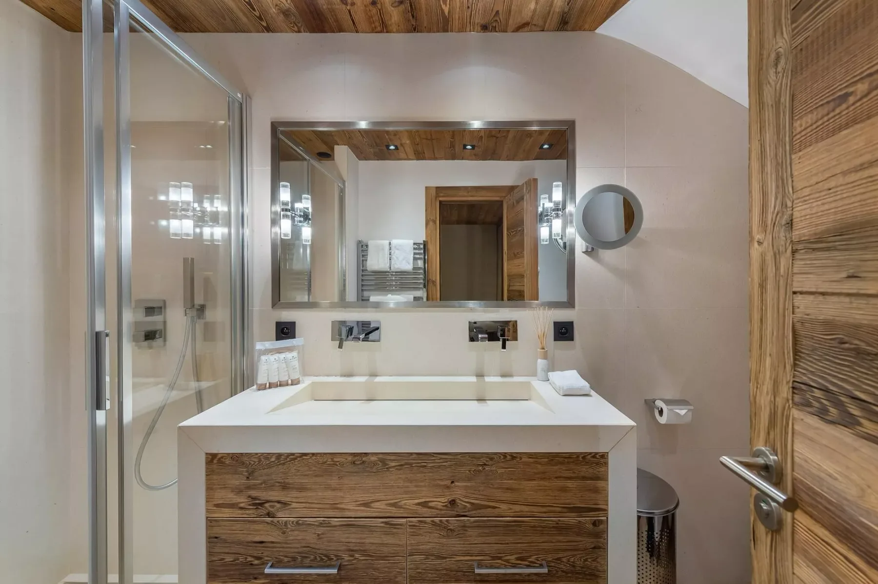 Un lavabo de baño con un espejo amplio y una ducha de vidrio.