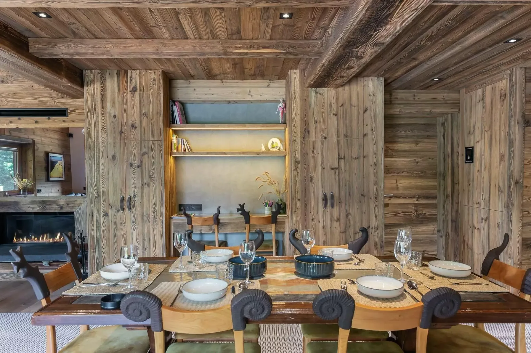 Un comedor rústico con una mesa larga con vajilla y una estantería de madera.