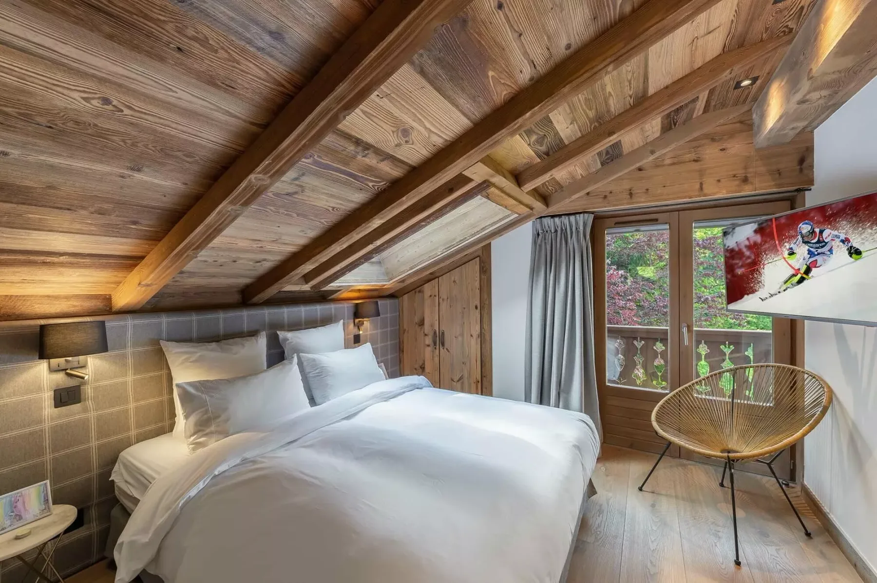 Un dormitorio con ropa de cama blanca bajo un techo inclinado de madera.