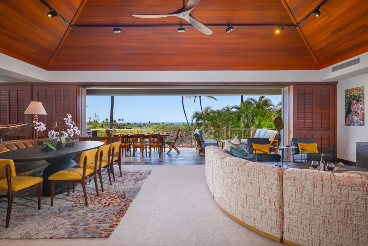 Una sala-comedor de planta abierta da a un patio con palmeras al fondo.