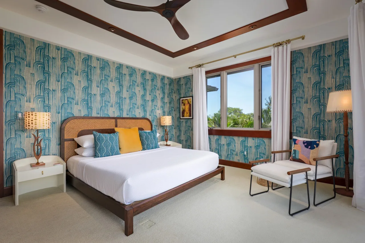 Un dormitorio con una cama grande, paredes azules estampadas y una ventana.