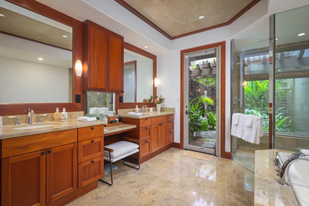Un baño amplio con muebles de madera y puertas de vidrio que dan a la vegetación.