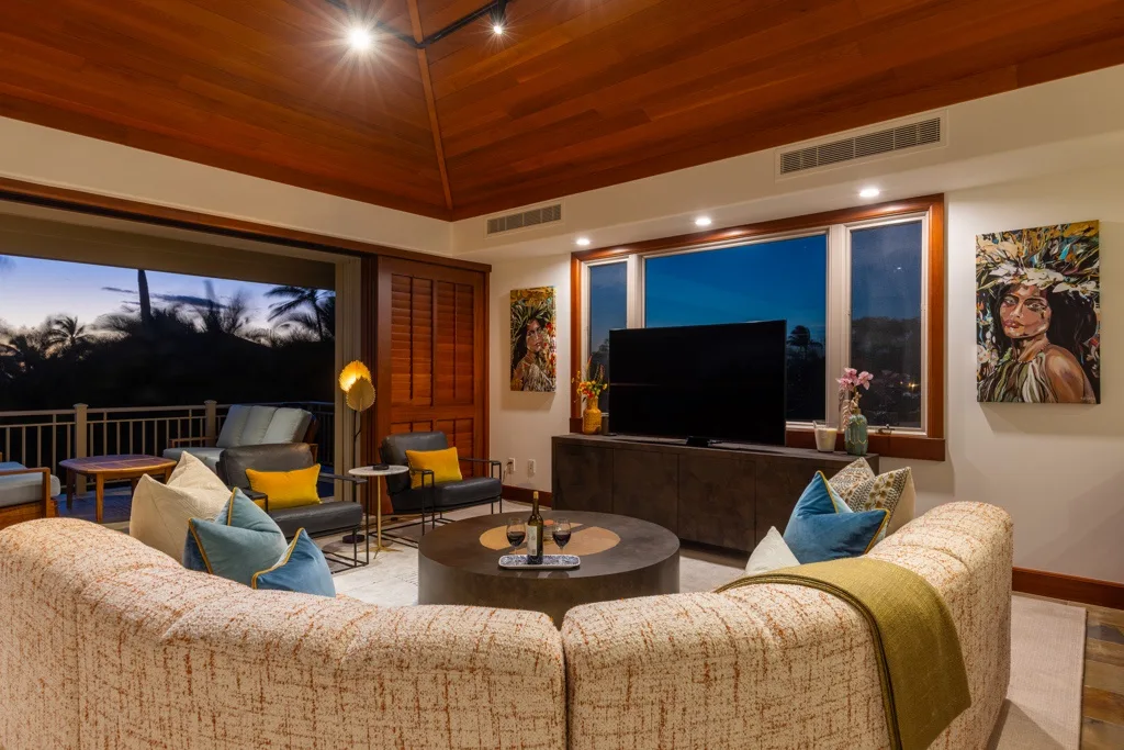Una sala de estar con asientos dispuestos alrededor de un televisor y una mesa de centro.