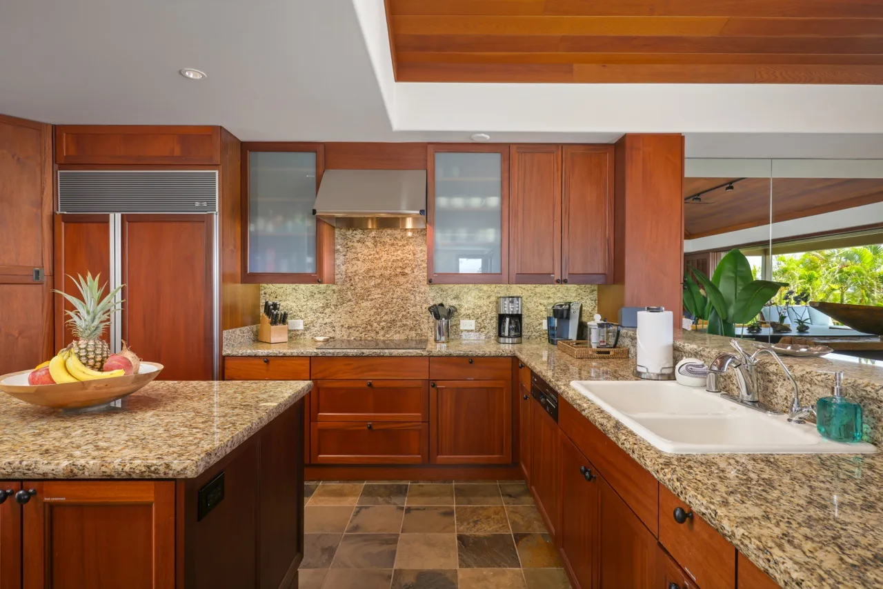 Una cocina de tonos cálidos con gabinetes de madera, encimeras de piedra y un fregadero.
