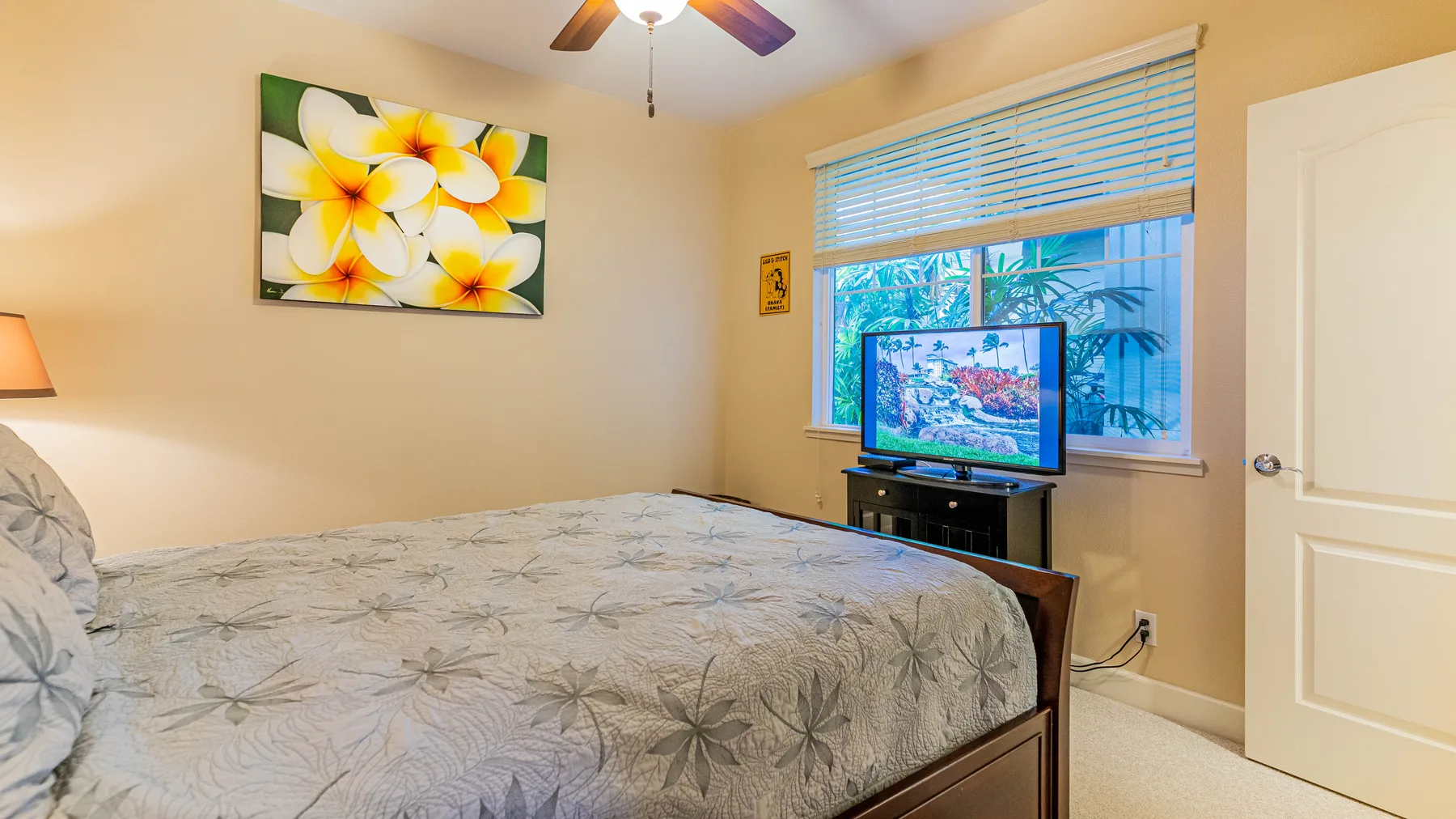 A bedroom with a bed, a television, and a window with blinds.