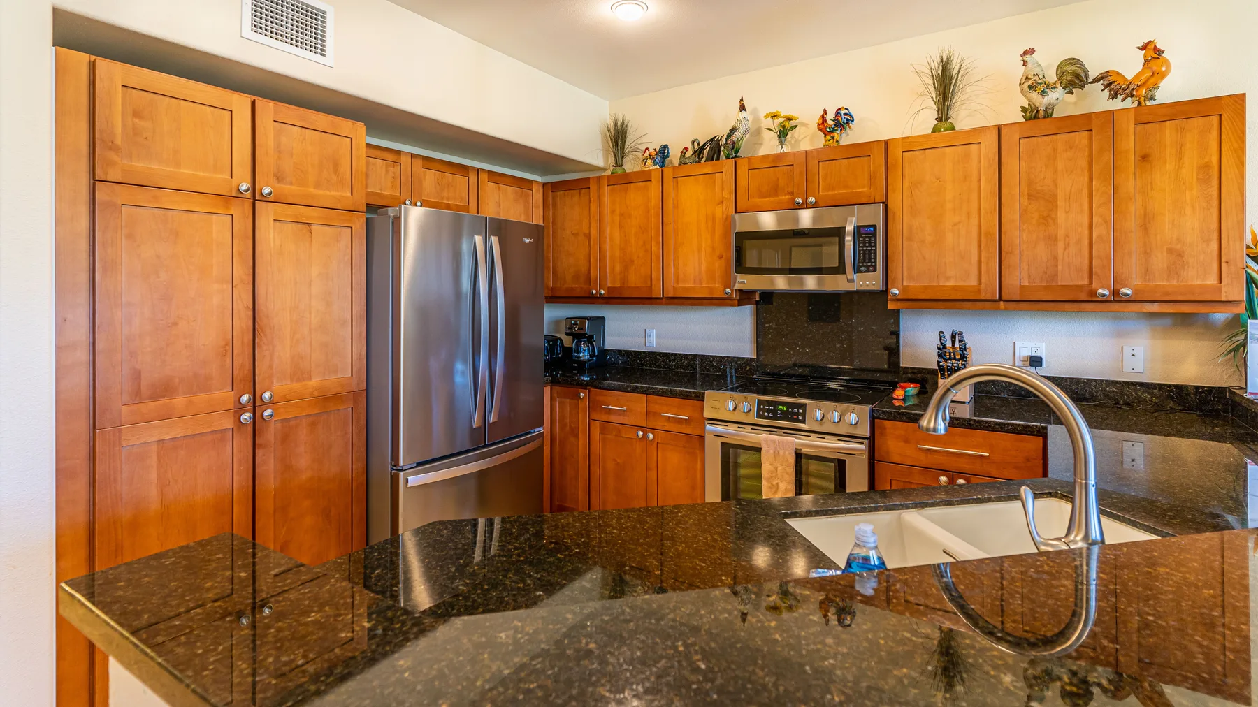 A kitchen with wooden cabinets, stainless steel appliances, and dark countertops.