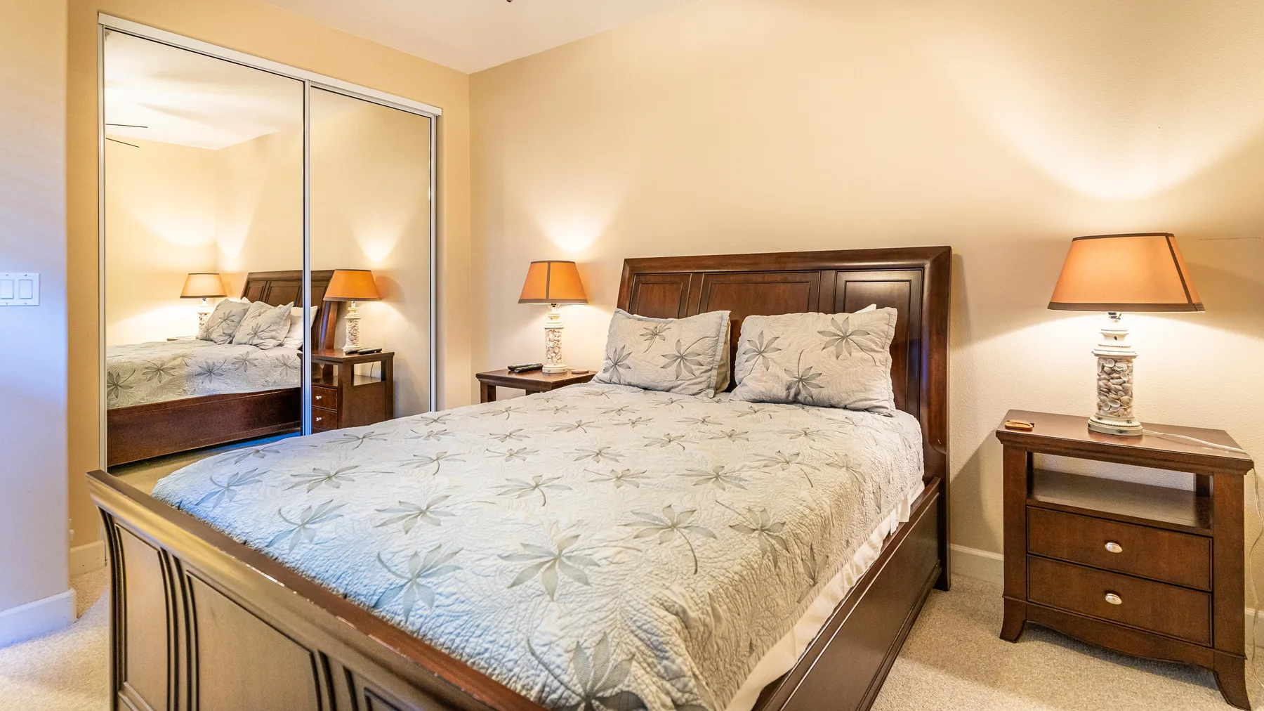 A bedroom with a wooden bed, patterned bedding, and bedside tables.