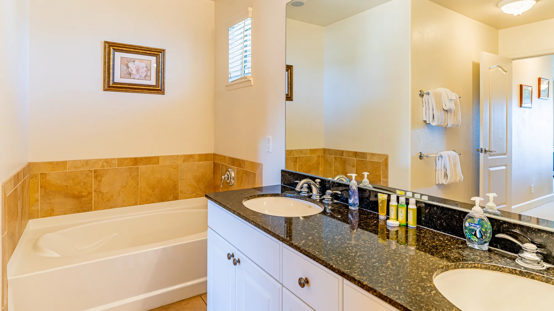 A bathroom with a bathtub, double vanity, and wall-mounted towel bars.