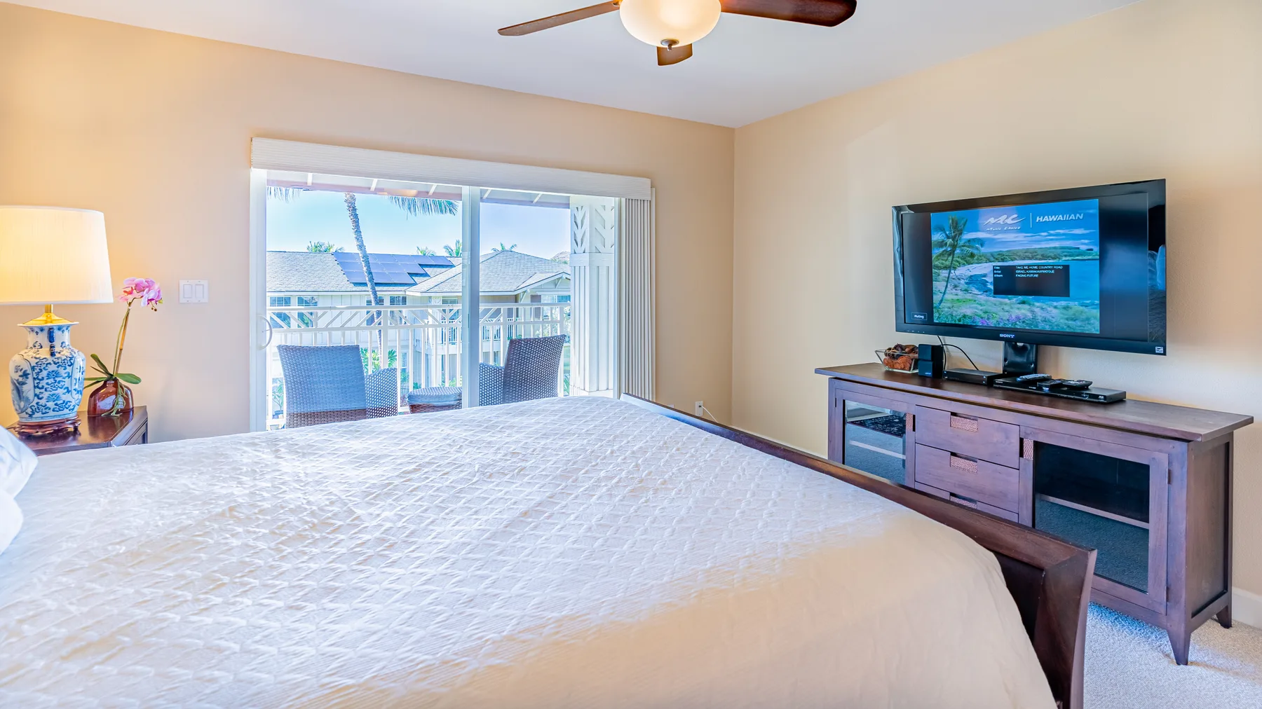 A bedroom with a large bed, sliding glass doors, and a television on a cabinet.