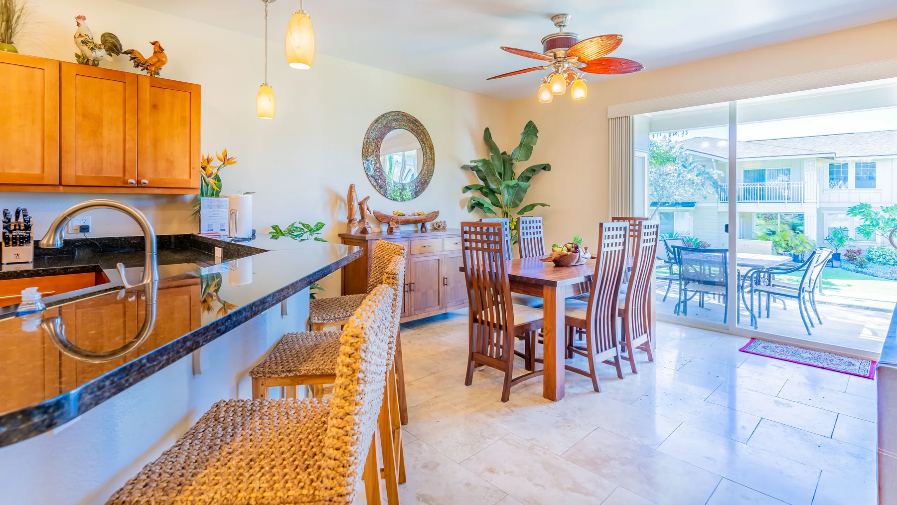 A bright dining area opens onto a patio, with a kitchen counter in the foreground.