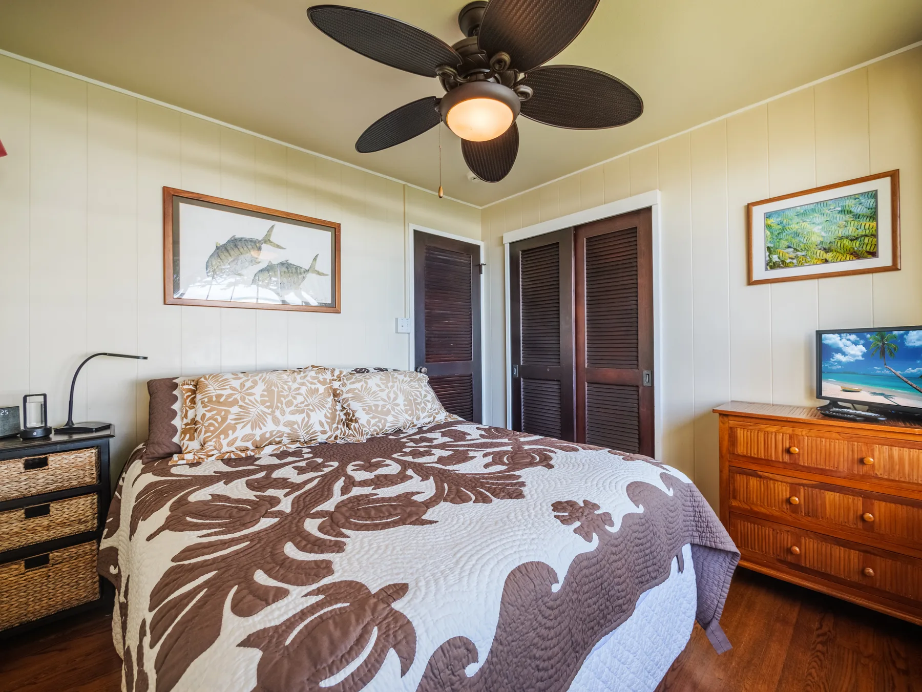 A bedroom with a bed covered in a brown-and-white patterned quilt.
