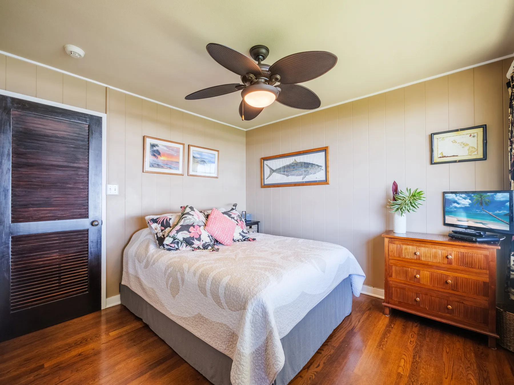 A bedroom with a bed, wall art, and a wooden dresser.