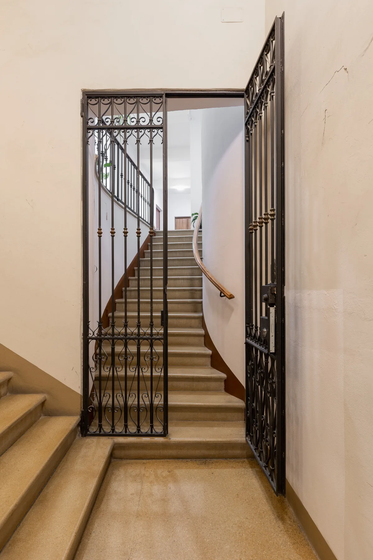 A staircase rises behind an open decorative metal gate.