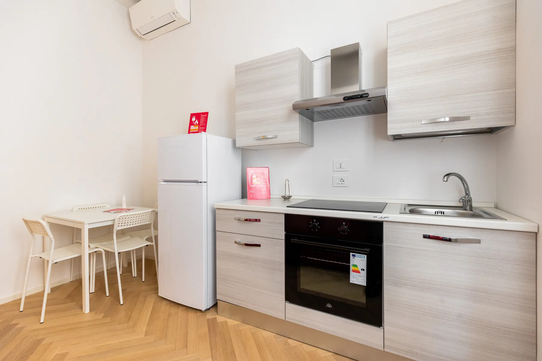 A bright kitchen with light wood cabinets, an oven, and a small dining table.