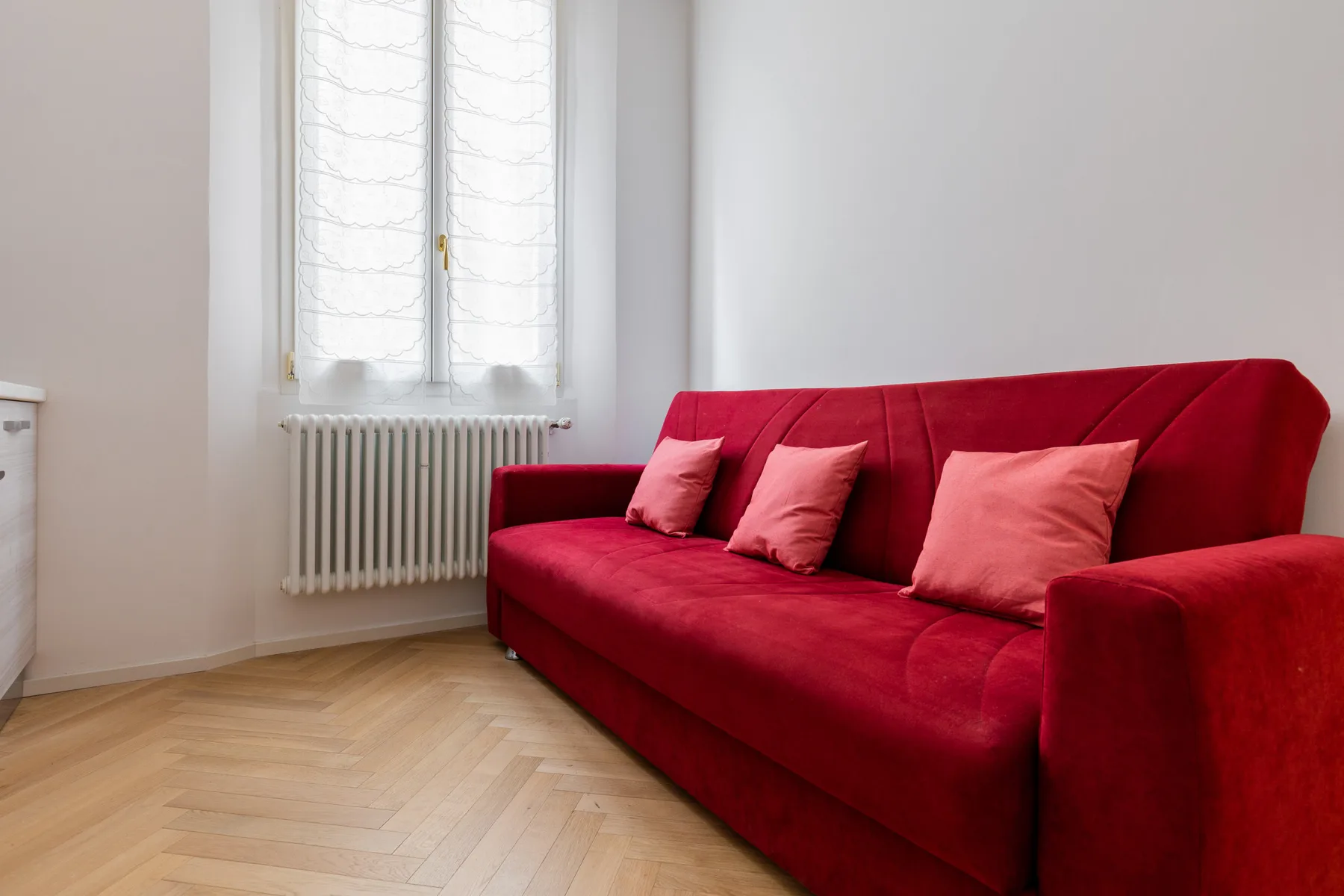 A bright living room with red seating beside a window.