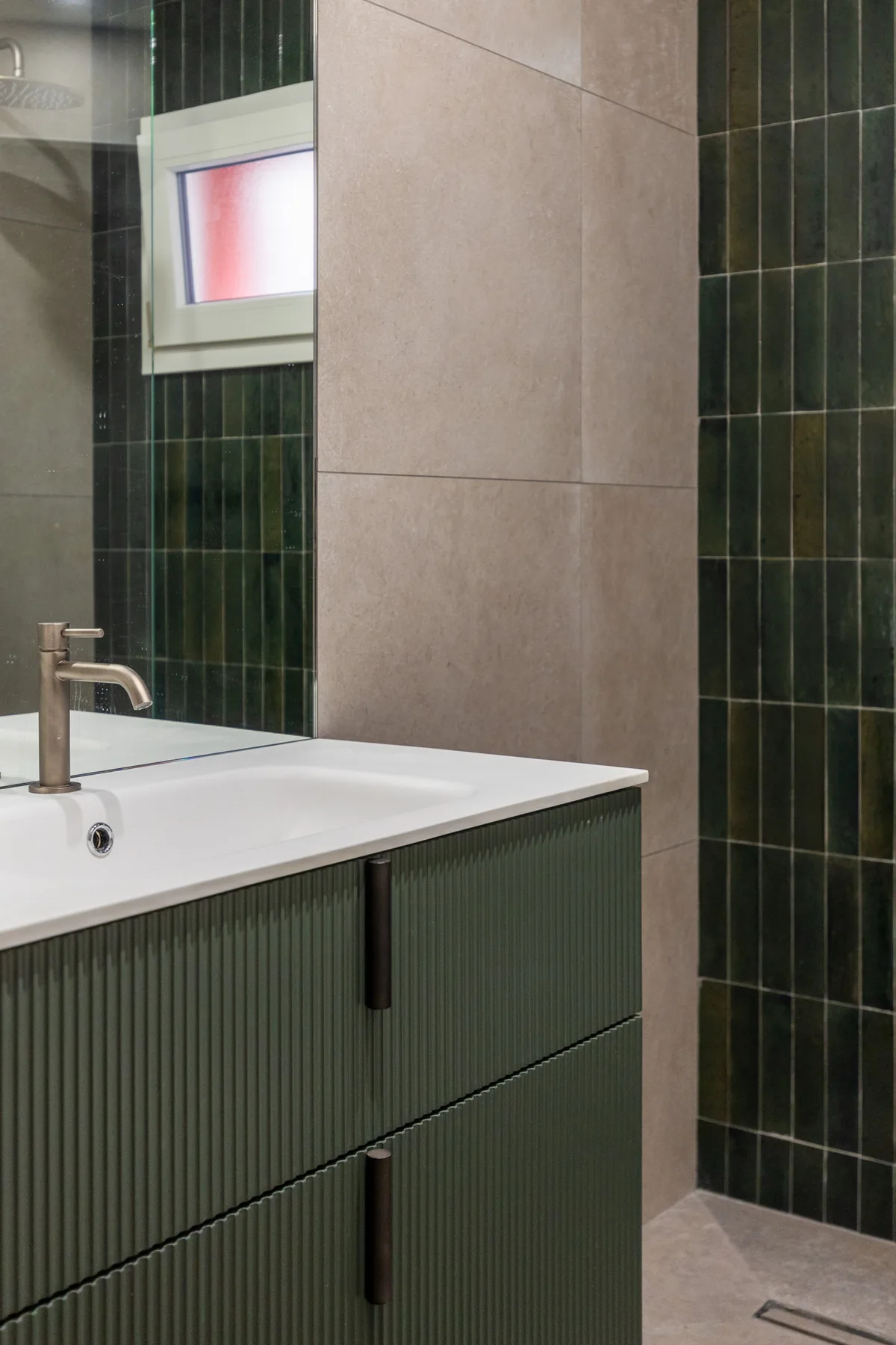 A bathroom vanity with a sink stands beside dark tiled walls.