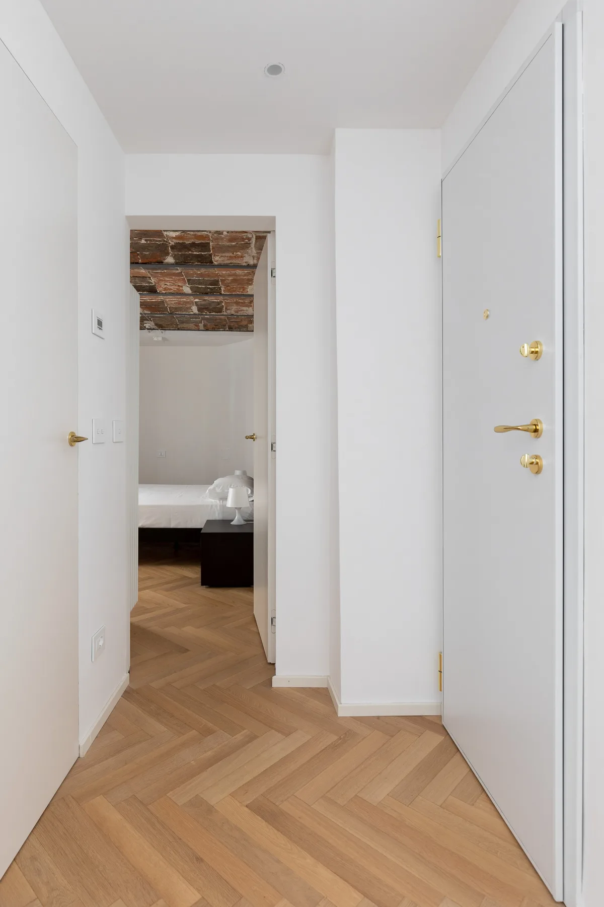 A bright hallway with light wood flooring and open doors.