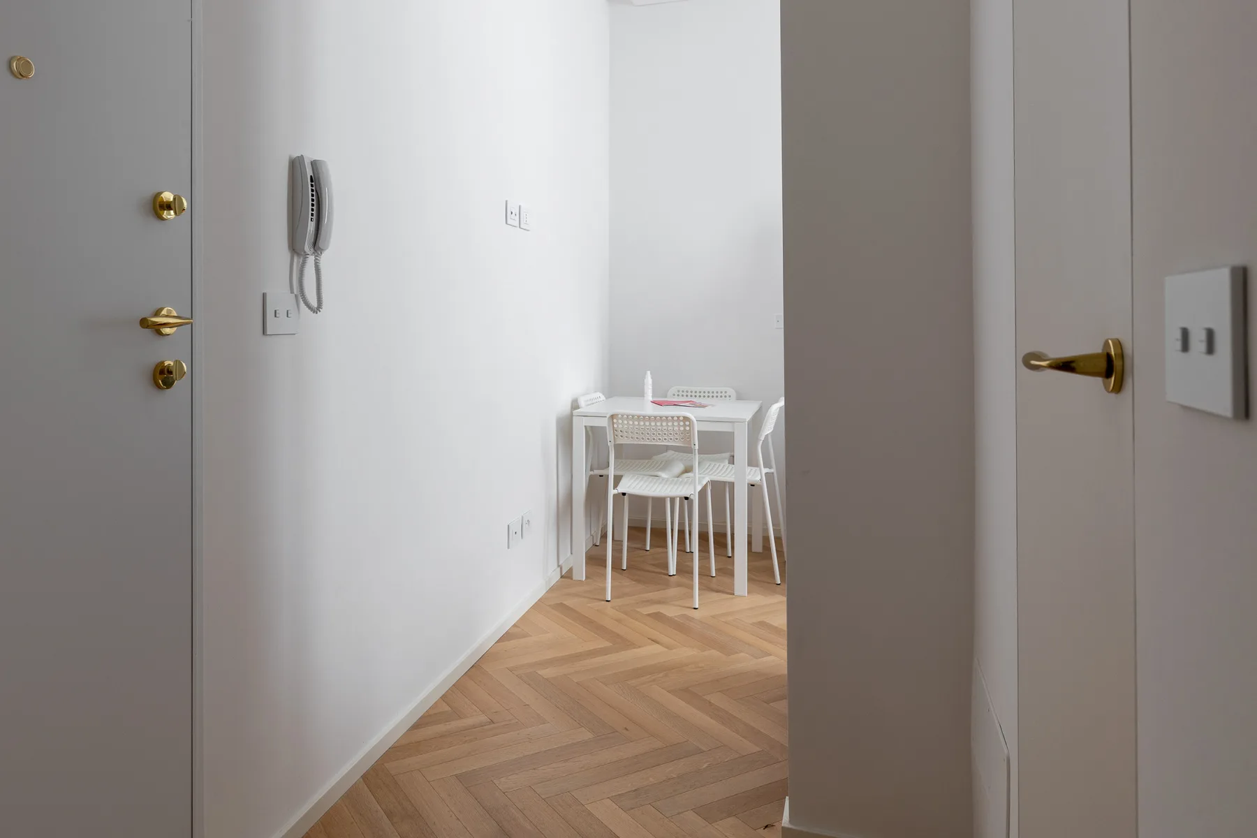 A small dining area with white chairs and a table sits beyond the doorway.