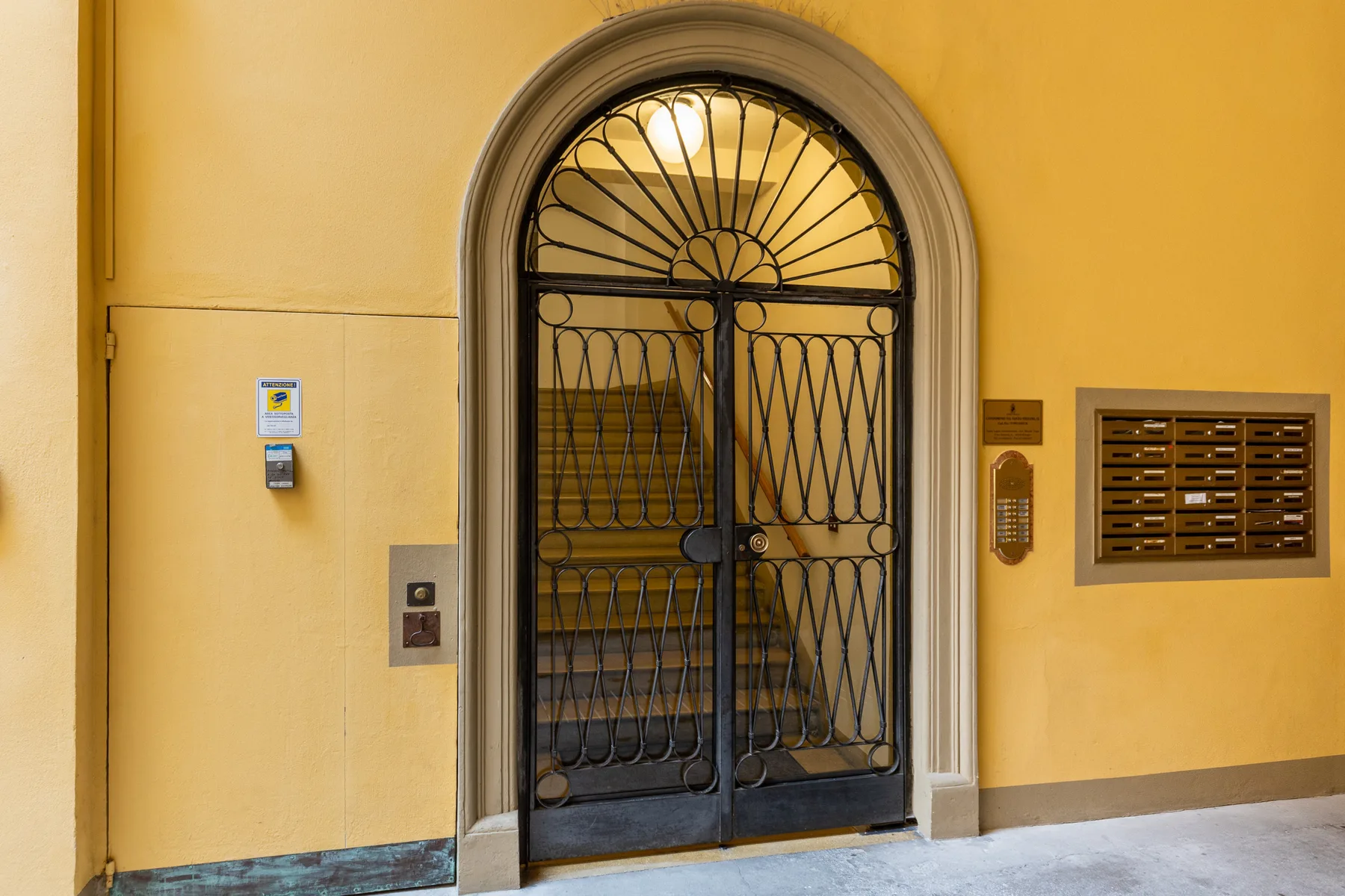 An arched entrance with a decorative metal gate and a mail slot panel.