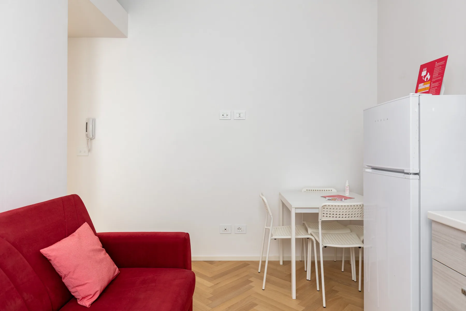 A bright dining area with a small table and chairs beside a refrigerator.
