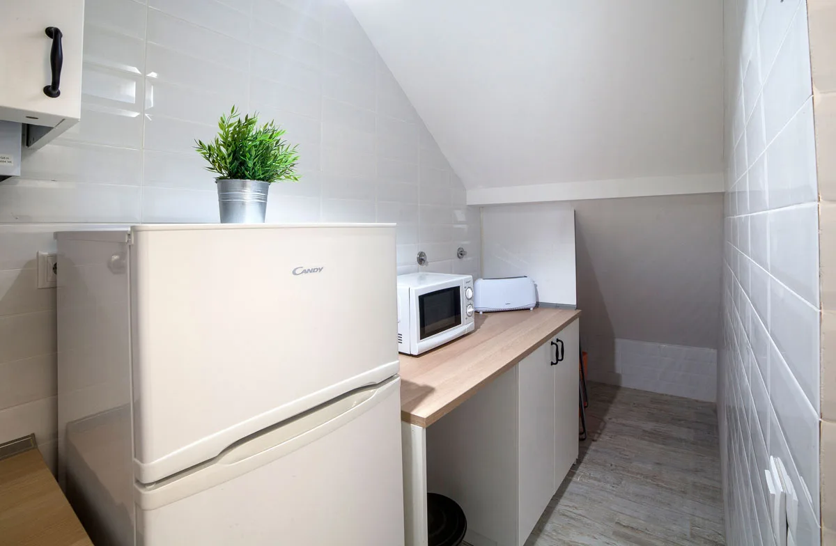 A compact kitchen with a refrigerator, countertop, and microwave.