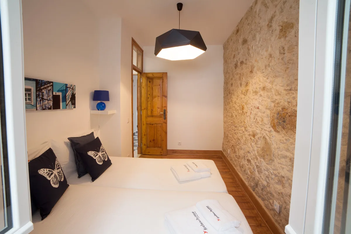 A bedroom with a bed beside an exposed stone wall.