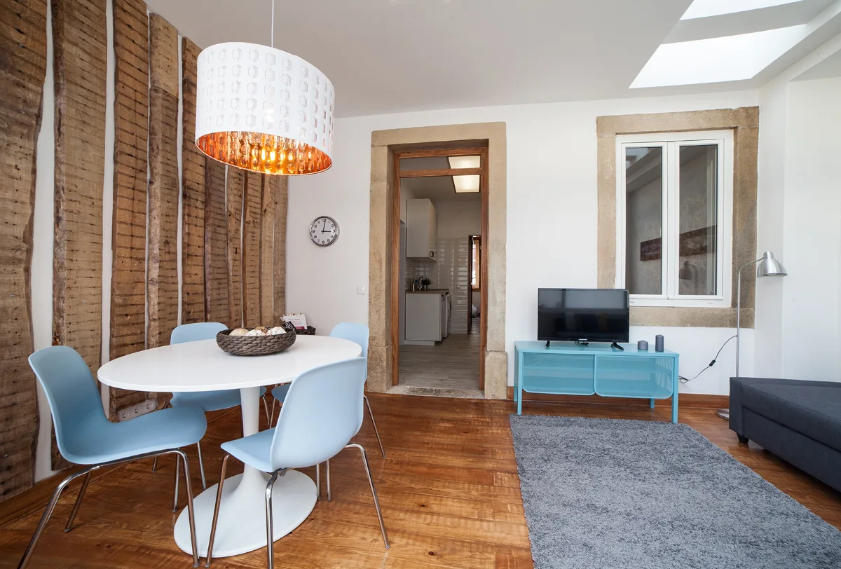 A dining and living area with a table, seating, and a television.