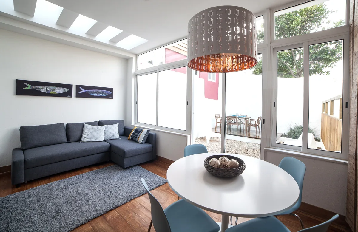 A bright living room with a gray seating area and a round dining table.