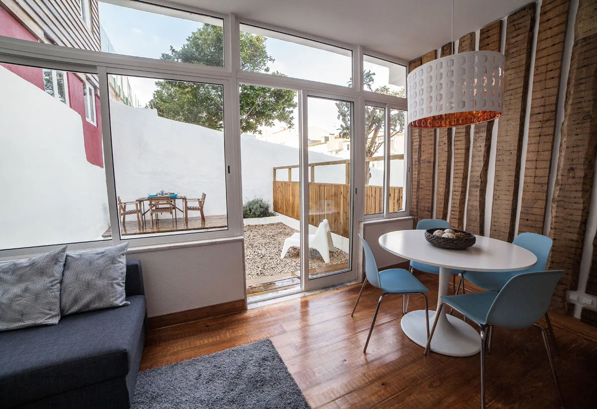A dining area with blue seating and large glass doors opening onto a small patio.