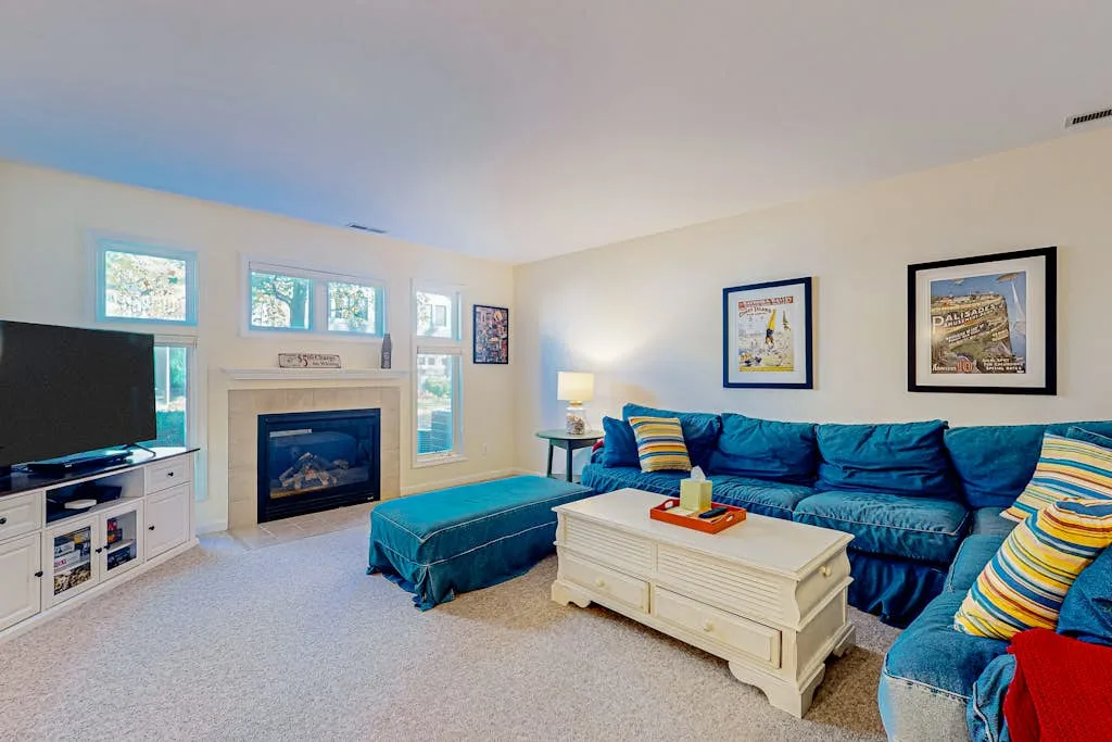 A bright living room with blue seating, a fireplace, and a white coffee table.