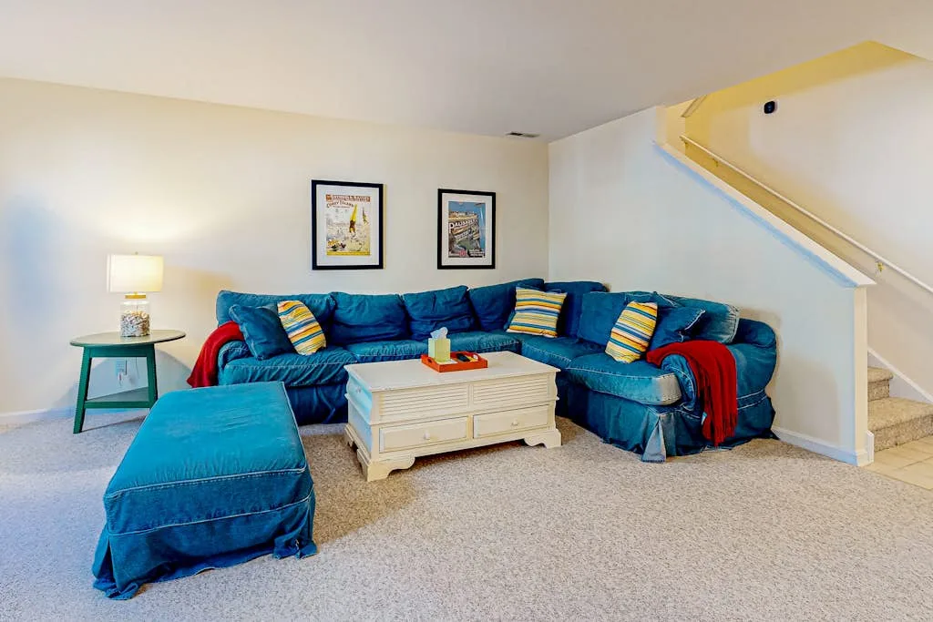 A living room with blue seating, a coffee table, and a staircase.