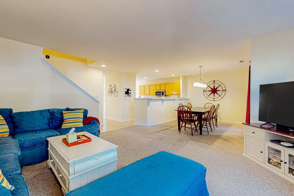 A bright living and dining area with blue seating and an open kitchen.