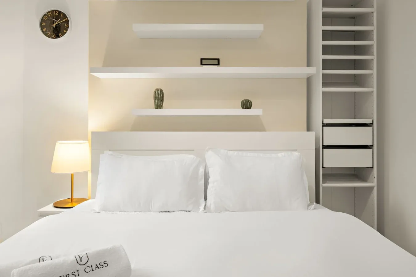 A bedroom with a neatly made bed and built-in shelving.