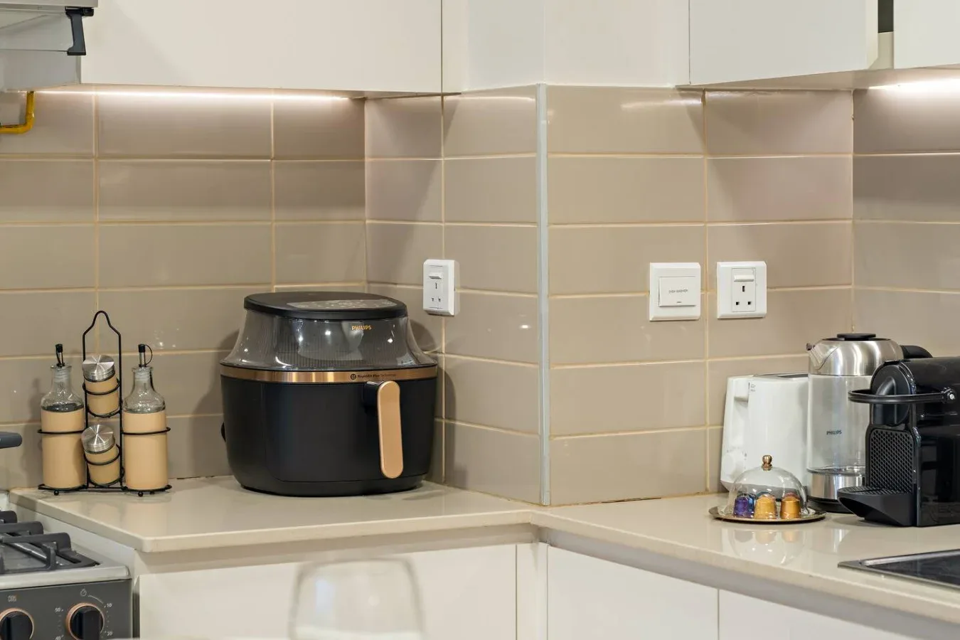 A kitchen countertop with a multicooker and small appliances beneath tiled walls.