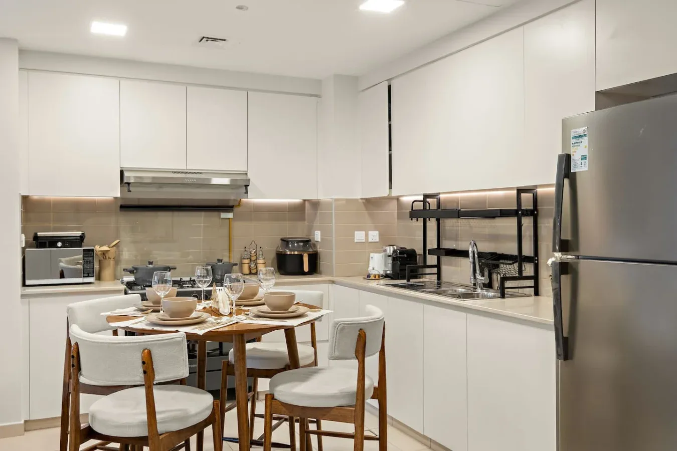 A bright kitchen with white cabinets and a dining table set with dishes.