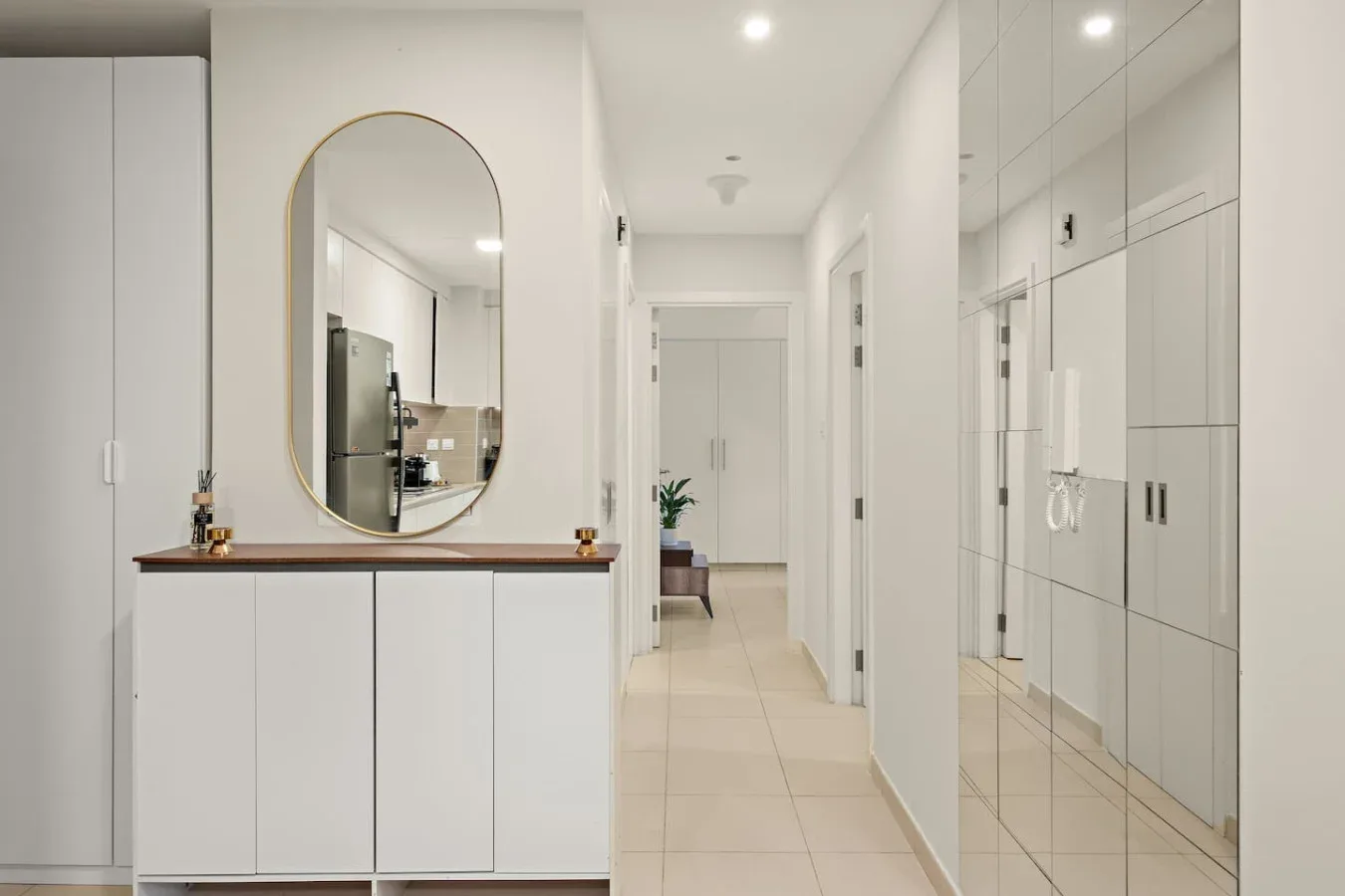 A bright hallway with a console and a tall oval mirror.