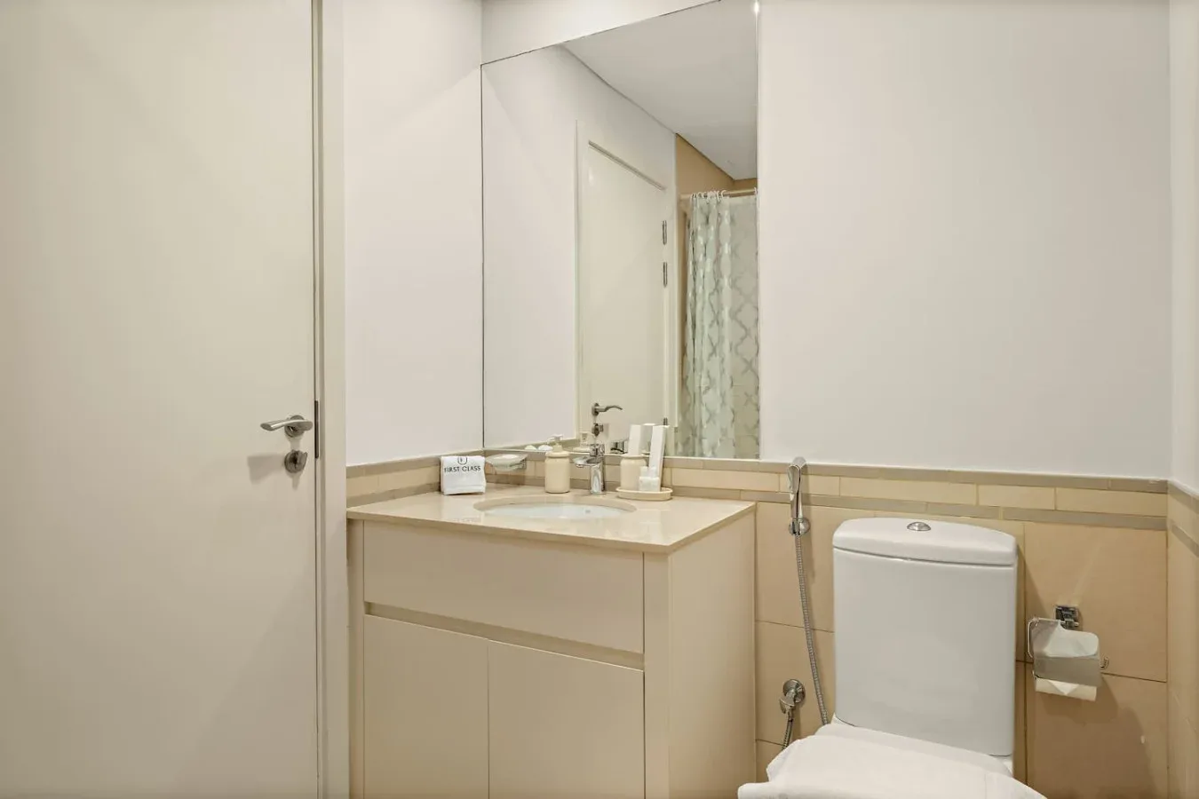 A bathroom vanity and toilet sit beneath a large mirror.
